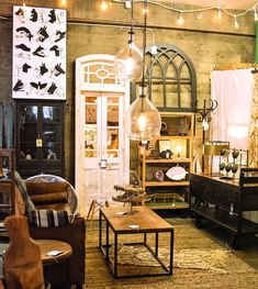 a living room filled with lots of furniture and lights hanging from the ceiling above it