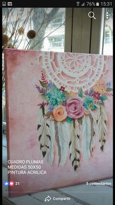 a pink canvas with flowers and feathers painted on the side, in front of a window