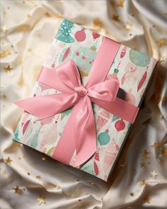 a present wrapped in pink ribbon on top of a bed