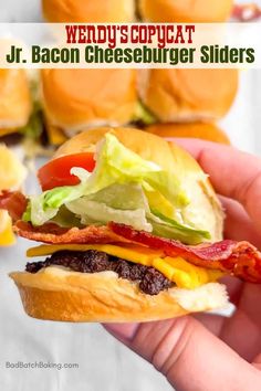 a hand holding a bacon cheeseburger slider