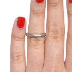 a woman's hand with a red manicure and silver ring on her finger