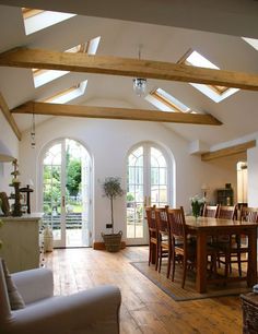 an open living room and dining area with wooden floors, vaulted ceilings, and white walls