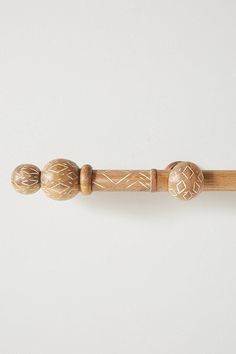 a close up of a wooden handle on a white wall with wood bead ends