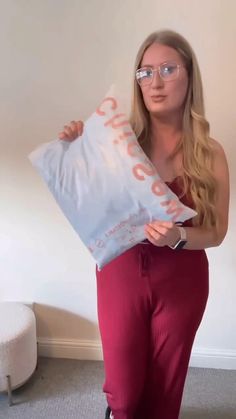 a woman in red pants and glasses holding a bag with the word shop on it