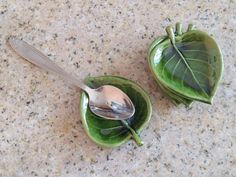 two green leaf shaped dishes with spoons in them