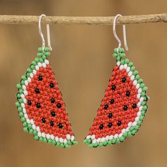 a pair of watermelon seed beaded earrings hanging from a branch