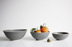 three bowls with oranges in them sitting on a table next to each other,