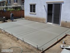 a man standing on top of a cement slab in front of a house under construction