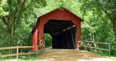 a large red covered bridge in the woods