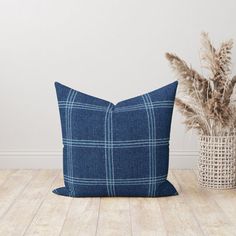 a blue pillow sitting on top of a wooden floor next to a potted plant