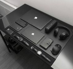 an apple laptop, headphones and other electronics on a table in black and white