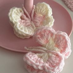 two crocheted baby booties on a pink plate