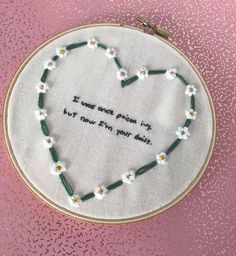 a heart - shaped embroidery with words written on it and daisies in the hoop