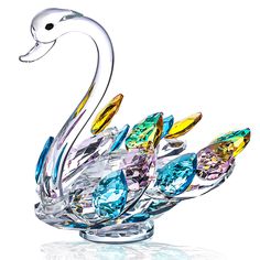 a glass swan figurine sitting on top of a white surface with blue and yellow crystals