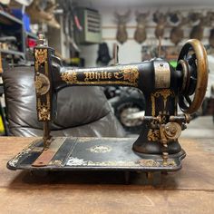 an old sewing machine sitting on top of a wooden table next to a leather couch