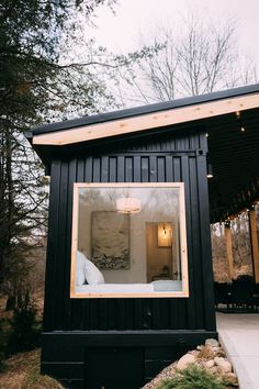 a small black cabin with a bed in the window