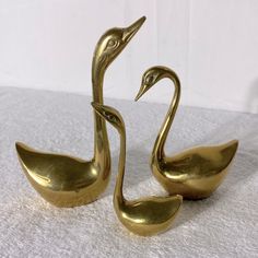 two brass swan figurines sitting next to each other