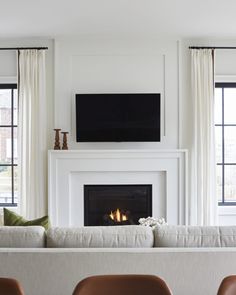 a living room filled with furniture and a flat screen tv mounted above a fire place