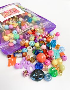 a plastic container filled with lots of different colored beads and bead charms on top of a white surface