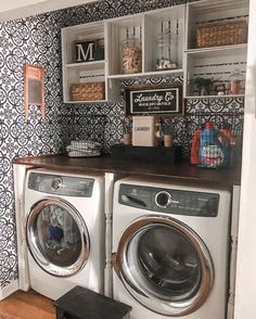 a washer and dryer sitting next to each other in a room with black and white wallpaper