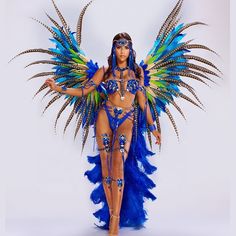 a woman in a blue and green costume with feathers on her head is posing for the camera