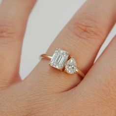 a woman's hand with an engagement ring and two pear shaped diamonds on it