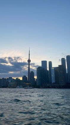 the city skyline is seen from across the water at dusk with clouds in the sky