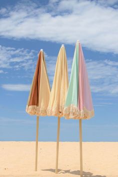 three beach umbrellas are lined up in the sand