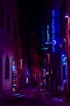 an alley way with neon lights and signs on the buildings