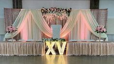 an image of a wedding stage setting with flowers on the head table and draping