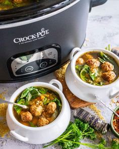 two white bowls filled with soup next to an open crock pot on a table