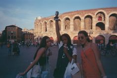 two women standing next to each other in front of an arena with people walking around