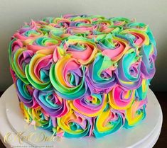 a multicolored cake with swirls on top sitting on a white platter