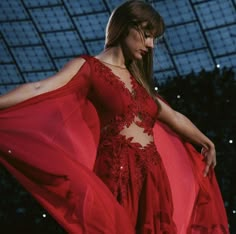 a woman in a red dress is walking down the runway with her hands on her hips