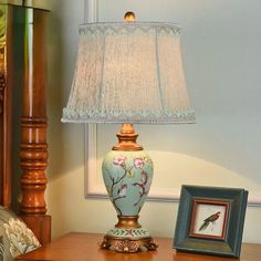 a lamp sitting on top of a wooden table next to a framed picture and a painting