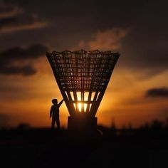 two people standing in front of a large metal structure at sunset with the sun setting behind them