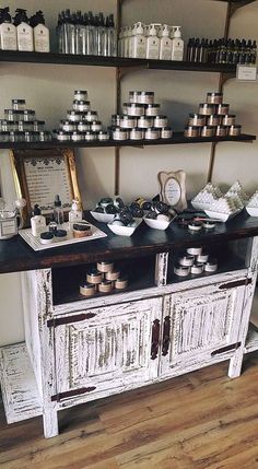 an old white cabinet with lots of jars on the top and shelves above it in a store