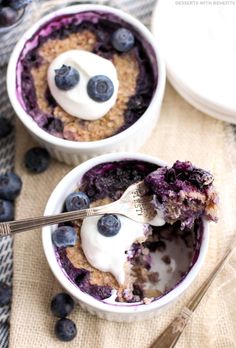 two bowls filled with blueberries and yogurt on top of a cloth covered table