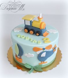 a birthday cake decorated with a train and birds on the top is blue, yellow and white