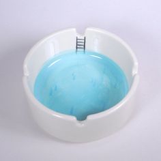 a white bowl filled with blue liquid on top of a table