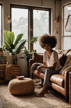 a woman sitting on top of a couch in a living room next to a window