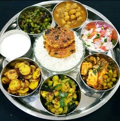 a silver plate topped with lots of different types of food on top of white rice