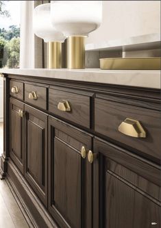 a kitchen with dark wood cabinets and gold pulls on the doors, along with white counter tops