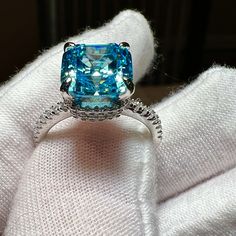 a fancy ring with a blue topaz surrounded by diamond accents on a white cloth