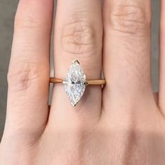 a woman's hand with a ring on it that has a pear shaped diamond in the center