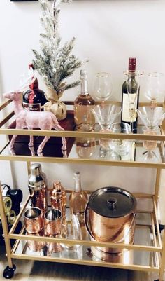 a bar cart filled with bottles and glasses on top of a wooden floor next to a christmas tree