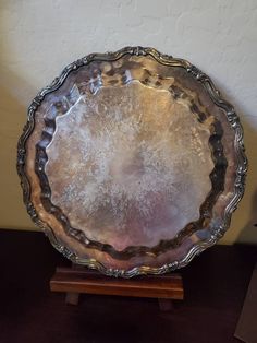 a silver plate sitting on top of a wooden stand