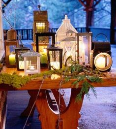 a table topped with lots of lit up lanterns and greenery on top of it