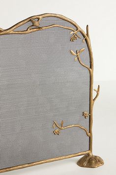 a gold metal fireplace screen with birds on it