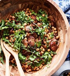 a wooden bowl filled with greens and chickpeas